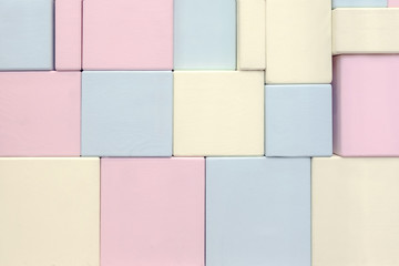 The wall of wooden rectangular shapes of different sizes of blue yellow and pink.