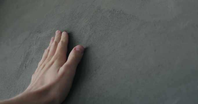 Slow motion man hand touches decorative concrete finish