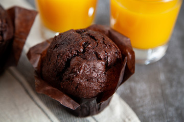 Chocolate muffin and two glasses of orange juice on the wooden table.
