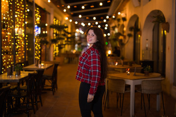 Fototapeta na wymiar Beautiful young woman in a red shirt on a background of a night city