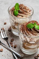 two portions Classic tiramisu dessert in a glass on concrete background