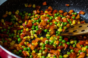 colorful vegetable stew from corn pepper and peas on frying pan, homemade dinner food concept 
