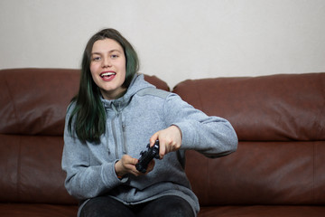 Beautiful brunette girl with dyed green hair with game console.