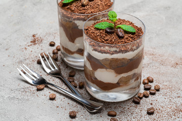two portions Classic tiramisu dessert in a glass on concrete background