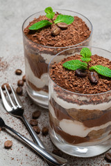 two portions Classic tiramisu dessert in a glass on concrete background