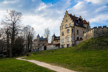 Fototapeta na wymiar Germany, German castle lichtenstein behind ancient walls of stone next to green meadow
