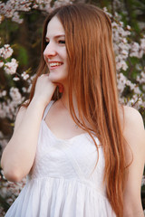 Naklejka premium Young caucasian women stay in cherry garden smile and look to the side