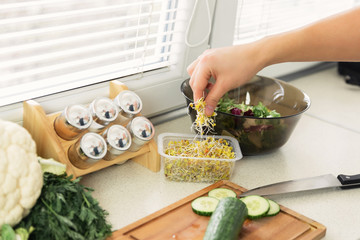A young man prepares a very healthy salad of fresh organic vegetables and herbs. He leads a healthy lifestyle.