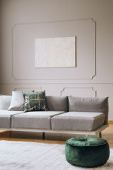 Abstract oil painting on grey wall with moldings in contemporary living room interior with grey long couch