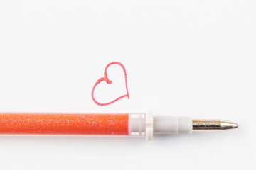 A red gel pen with sparkles and a heart painted on a white paper background. The concept of stationery for school, business and creative.