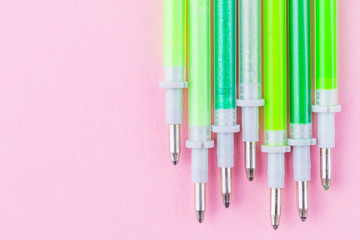 Gel paste for pens of green shades on a pastel pink background. The concept of stationery for school, business and creative. Copy space, flat lay, minimalism.