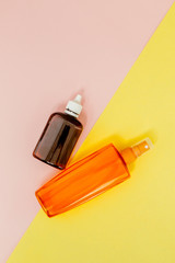 Bottle sunblock on bright square yellow and pink background. The concept of the resort at sea, summer time. Top view, flat lay, minimalism, copy space
