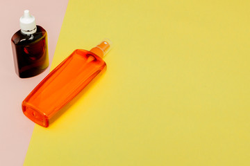 Bottle sunblock on bright square yellow and pink background. The concept of the resort at sea, summer time. Top view, flat lay, minimalism, copy space