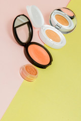 Make up products spilling on to a bright yellow and pink background with copy space