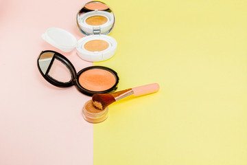 Make up products spilling on to a bright yellow and pink background with copy space