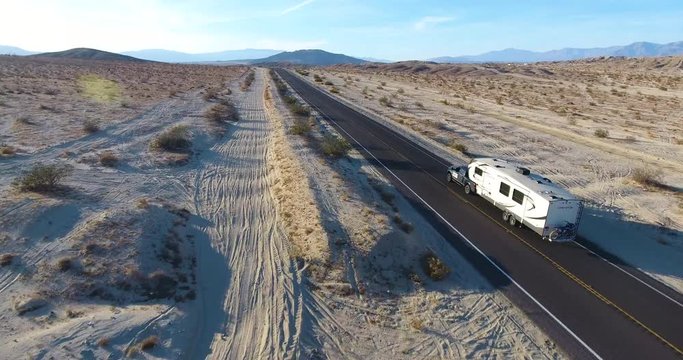 RV Fifth Wheel Driving On California Desert Road - Low Rear Aerial View Drone Shot