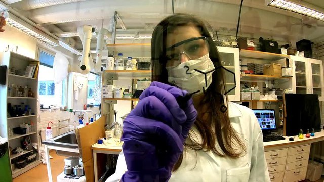 Beautiful European woman scientist working in a chemistry laboratory and drawing a heterocycle chemical structure