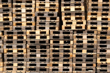 Pallets background. Stacks of rough wooden pallets at warehouse in industrial yard. Cargo and shipping concept.