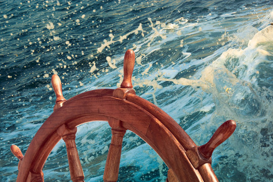 Wooden steering wheel at sea background