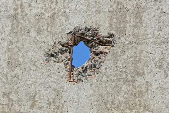blue hole on old gray concrete wall of a fence