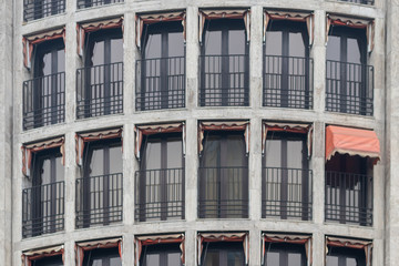 Altbaufassade mit kleinen roten Markisen, von denen eine einzige ausgefahren ist