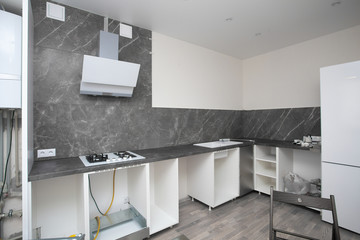 Installing new oven and gas stove in kitchen. Modern Interior in grey colors. Assembling kitchen furniture at home in new house.