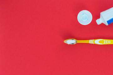 Toothbrush and toothpaste on a red background.