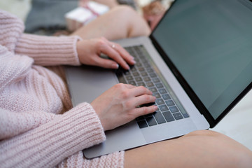 Christmas online shopping. Woman buys presents, prepare to xmas eve. Female with laptop, copy space on screen. Hot coffee, spice and almond cakes on tray. Cozy blanket. Toned image. Soft focus.