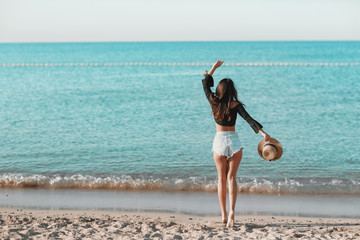 A girl in bikini standing on the beach. Summer holidays and vacation concept