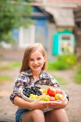 Girl in shirt and shorts with a basket of fruit. Girl farmer with apples and grapes. Concept of ecological food, person, fruit