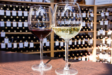 white and red wine in glasses on the background of bottles