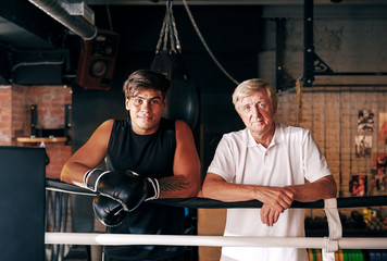 Portrait of a young boxer with his mature trainer standing at ring