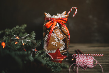 Homemade gingerbread in the glass jar with fir branches on the background, spices and decor. Holidays, winter, Christmas presents concept. Merry Christmas and Happy Holidays. Toned image. Soft focus.