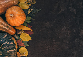 Fresh autumn seasonal vegetables and fruits on brown old background. Fallen leaves, red apples,...