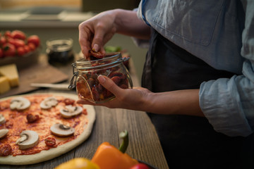 Fresh pizza with tomato and mushrooms. Homemade tasty pizza on dark wooden background. Raw dough for pizza with ingredients and spices on wooden rustic table. Traditional Italian food. Soft focus.
