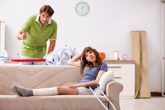 Husband helping leg injured wife in housework 