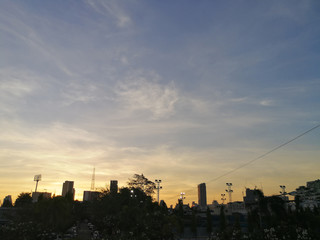 Fototapeta na wymiar City skyline at dusk with electricity transmission and light poles among modern buildings
