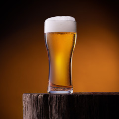 Glass of light beer on wooden table