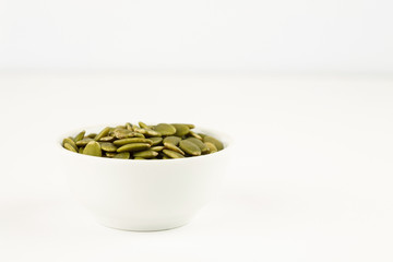 Peeled green pumpkin seeds in a white bowl