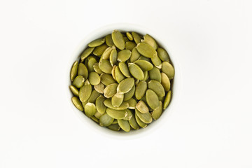 Peeled green pumpkin seeds in a white bowl