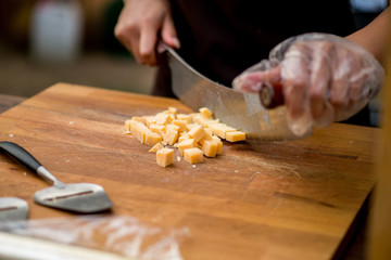 hands cut the cheese into pieces with a special knife