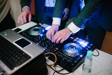A man stands at the DJ and works as a DJ.