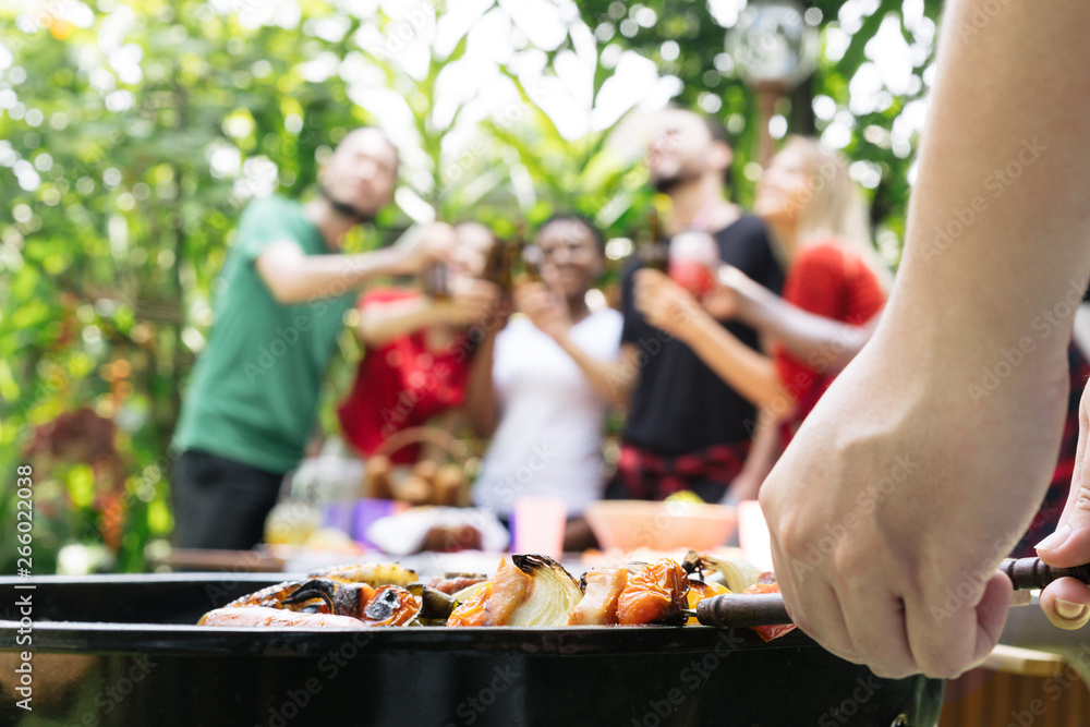 Wall mural hand of bbq grilling and friends having barbecue party, outdoors