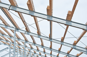 Metal frame of the new building with laid wooden beams fore roof. The fast-built designs from metal.