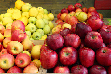 Red and yellow apples at the market. Many ripe apples on wooden background. Space for text