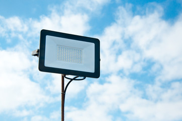 LED spotlight against the blue sky. Lighting area. The use of technology in modern construction.