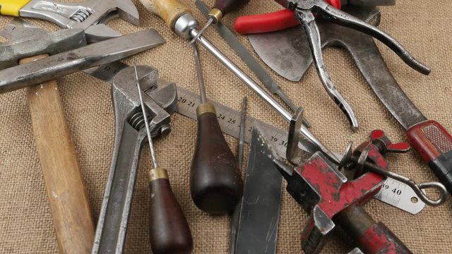 Awl is  being put on the old locksmith tools lying on the burlap, background