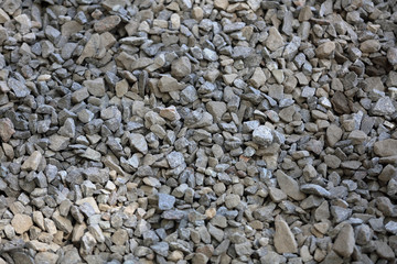 Gray textured surface of a heap of construction pebbles and gravel