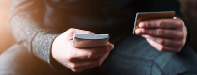 A woman holding a smartphone and credit card in her hands. The concept of online shopping or money transfer