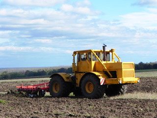 Tractor plows field. Tractor rides on the field and plows arable land.  Details and close-up.